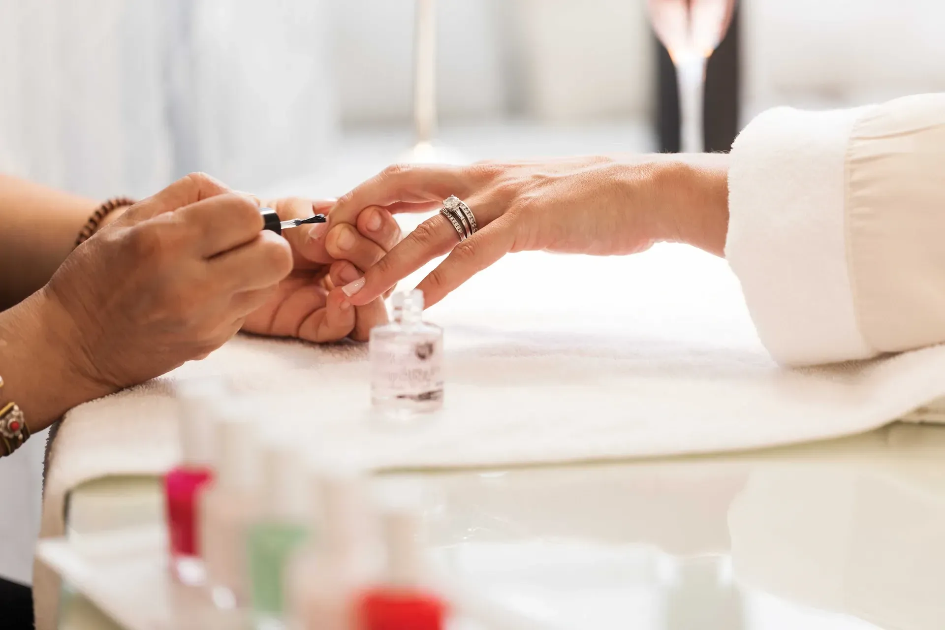 Una peluquera peina el cabello mojado en un salón. Hay otras personas al fondo.