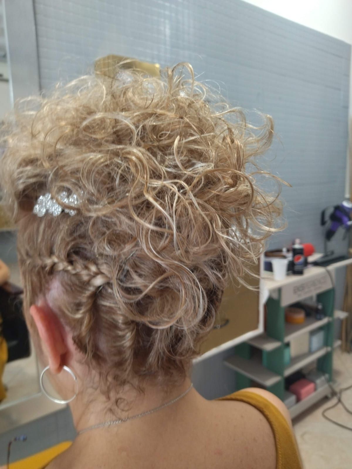 Mujer con peinado recogido rubio y rizado con trenzas y accesorios para el cabello.