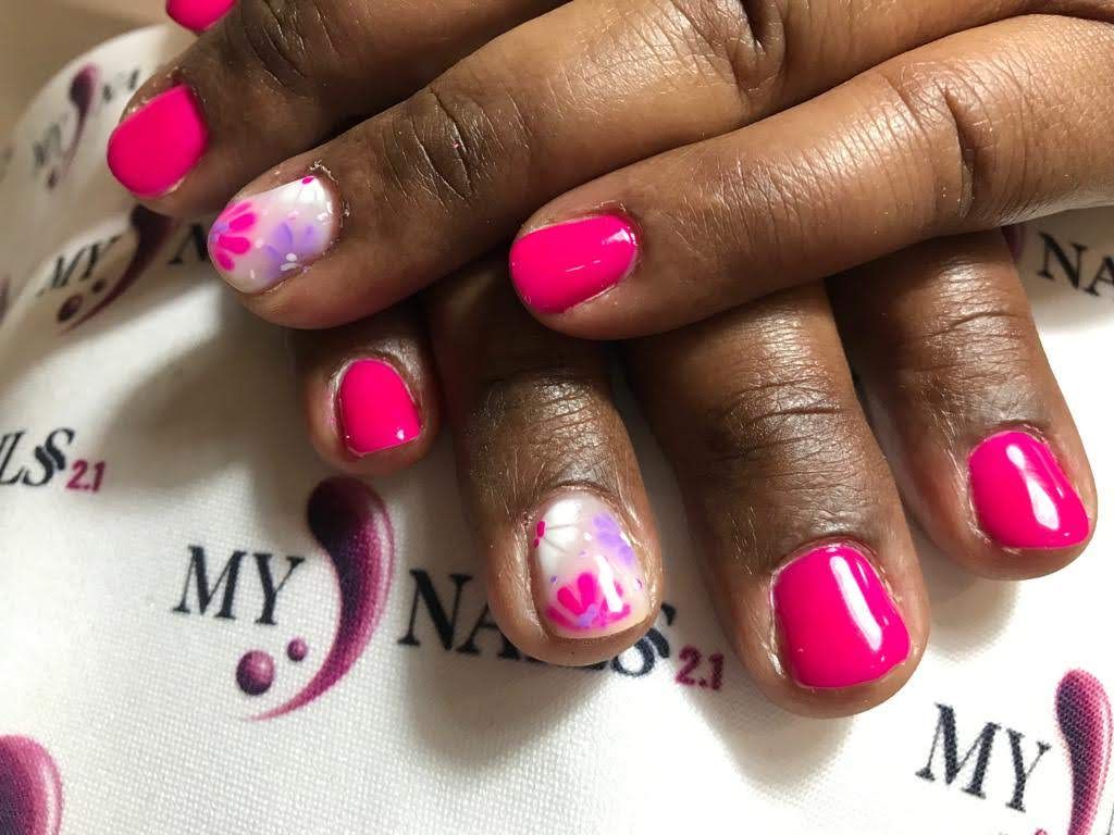 Manos con esmalte de uñas de color rosa brillante y diseño floral.