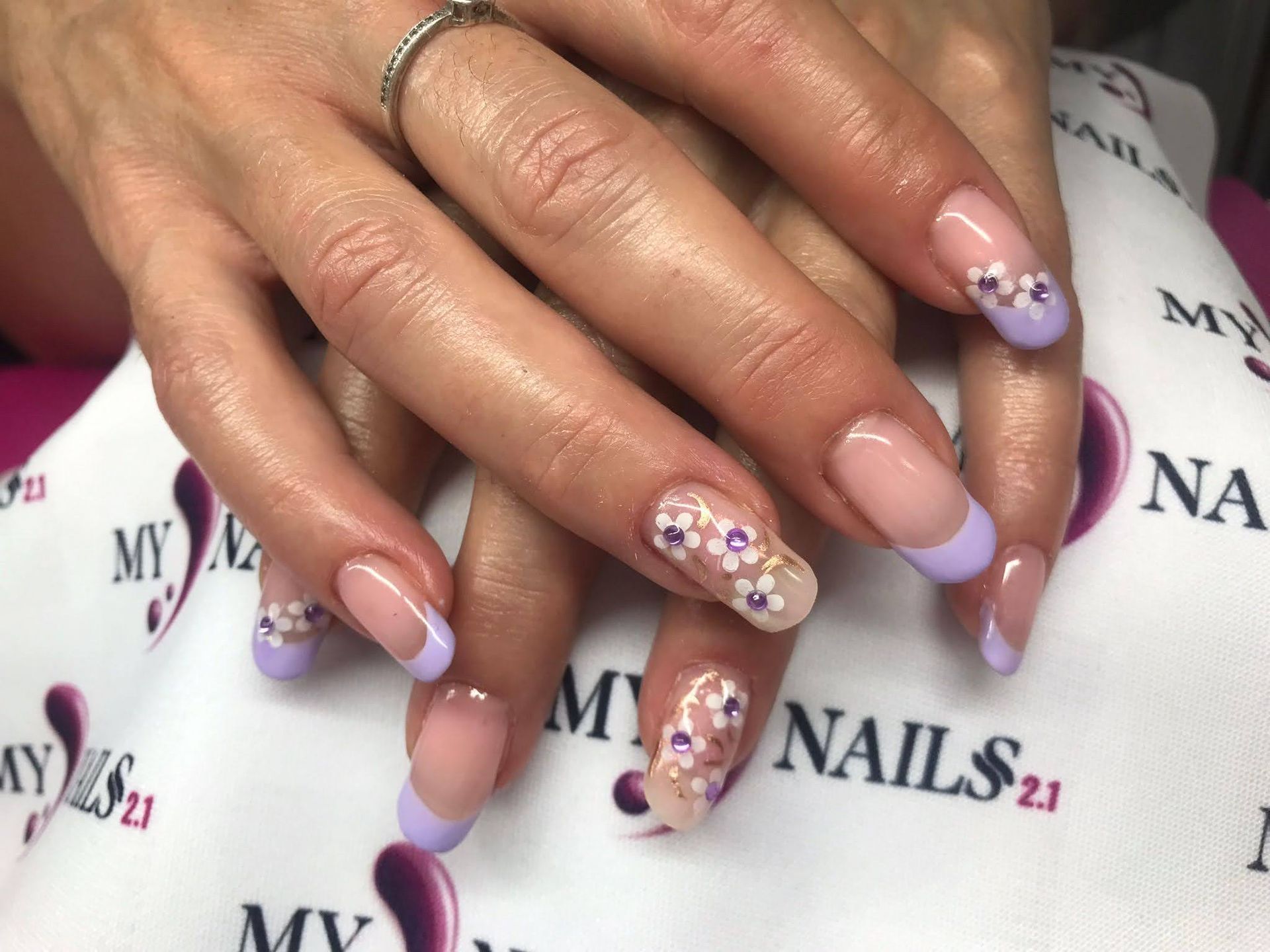 Manos con manicura francesa, puntas de lavanda y nail art con flores.