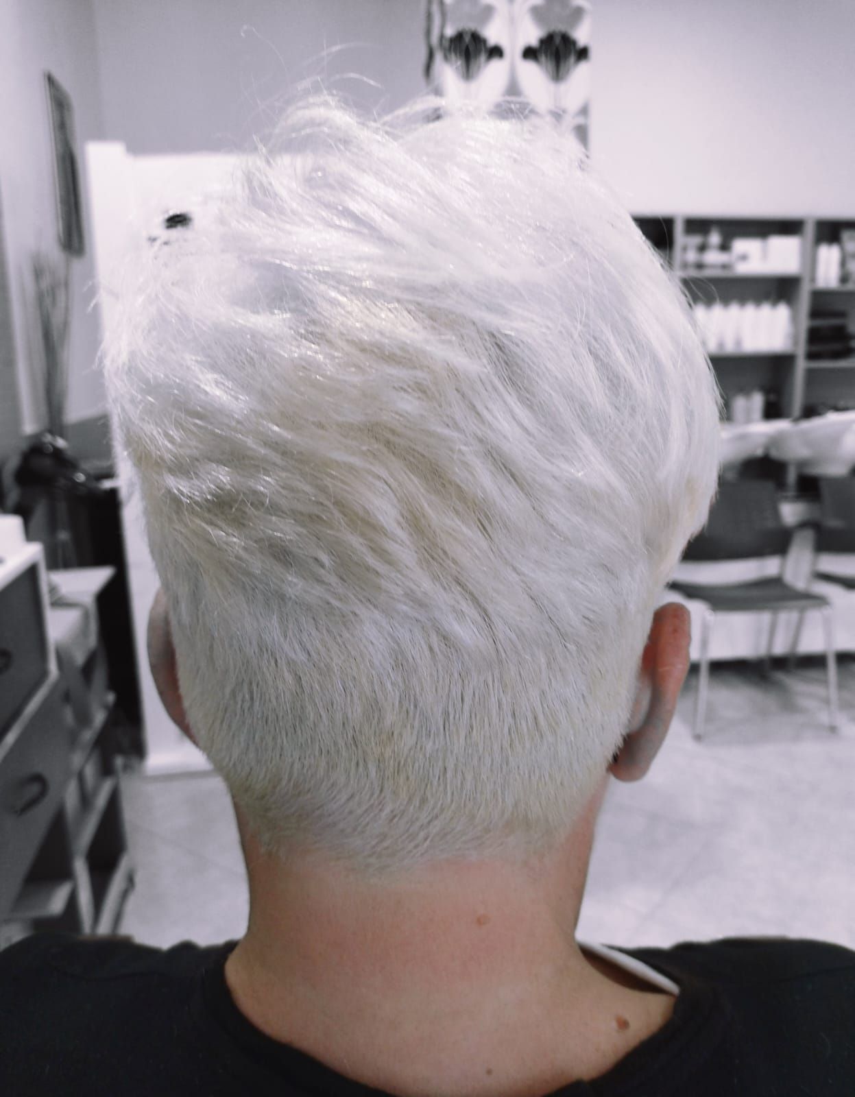 Primer plano de la parte posterior de la cabeza de una persona con cabello corto rubio platino y la nuca descolorida.