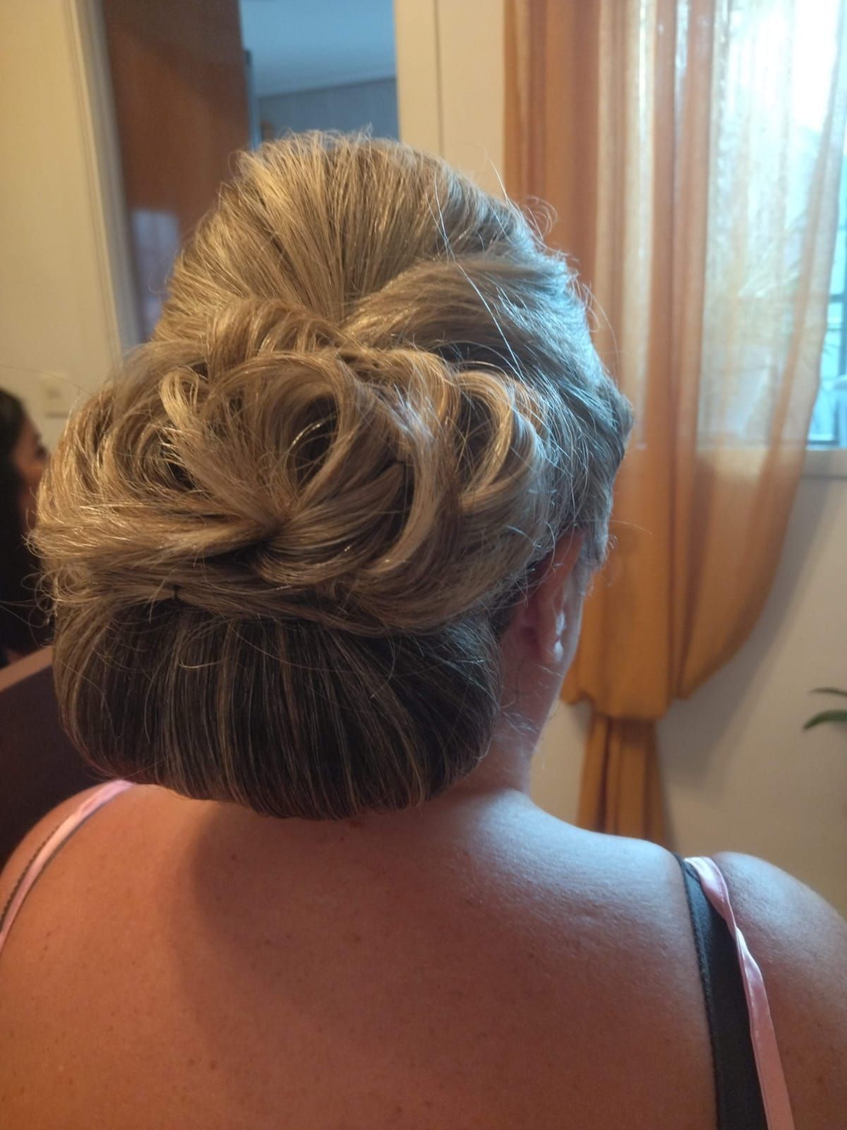 Peinado recogido en mujer de cabello rubio y gris; moño en la nuca.