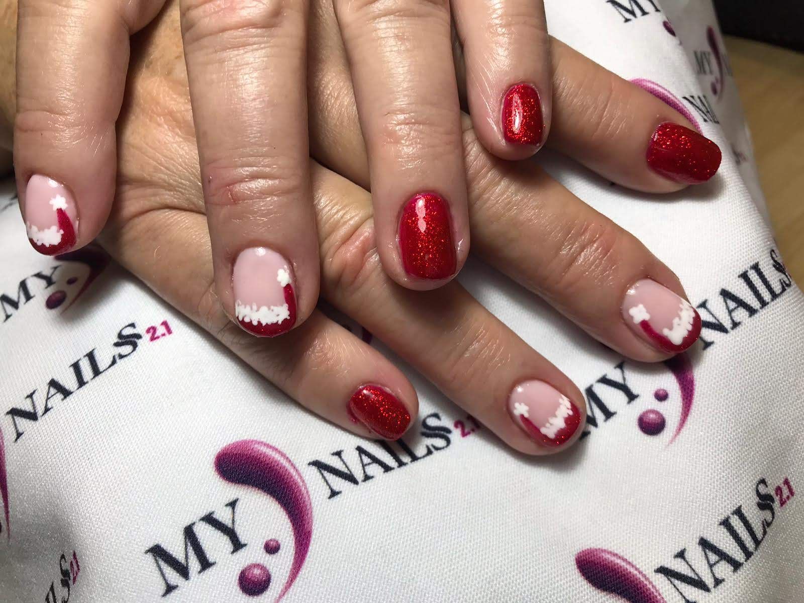 Manos con uñas de Halloween decoradas en rojo y blanco sobre una toalla blanca.