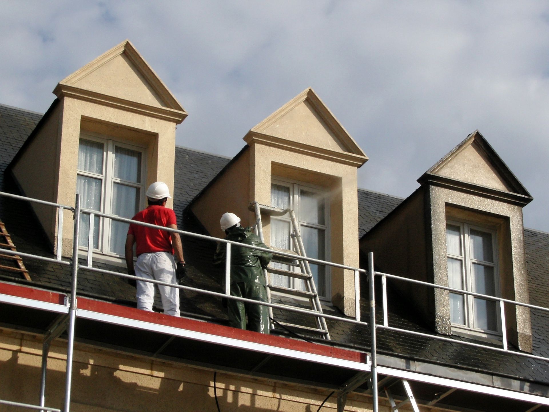 Deux hommes en train de repeindre une façade