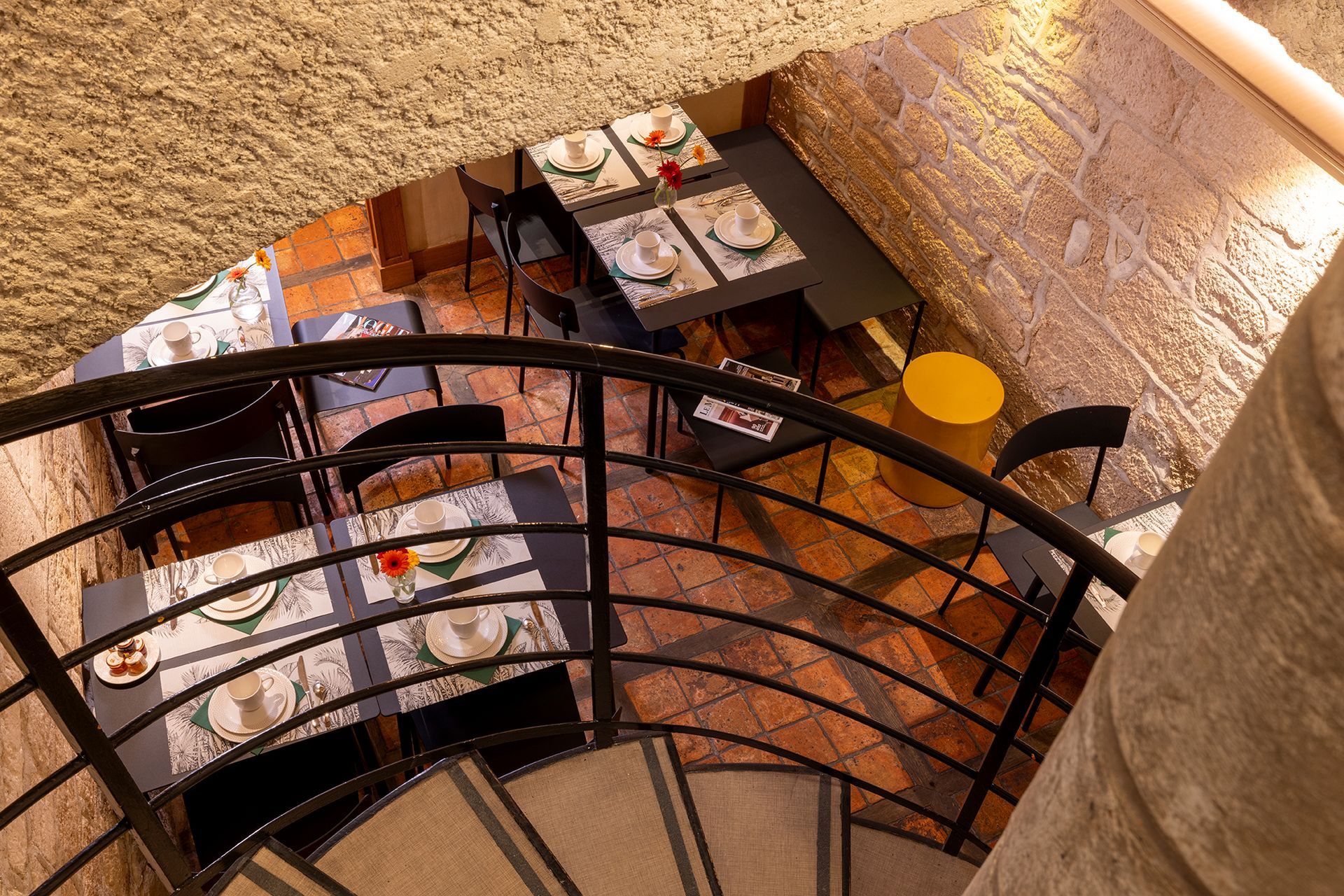 Intérieur du restaurant avec tables dressées pour le repas, visible depuis l'escalier en colimaçon.