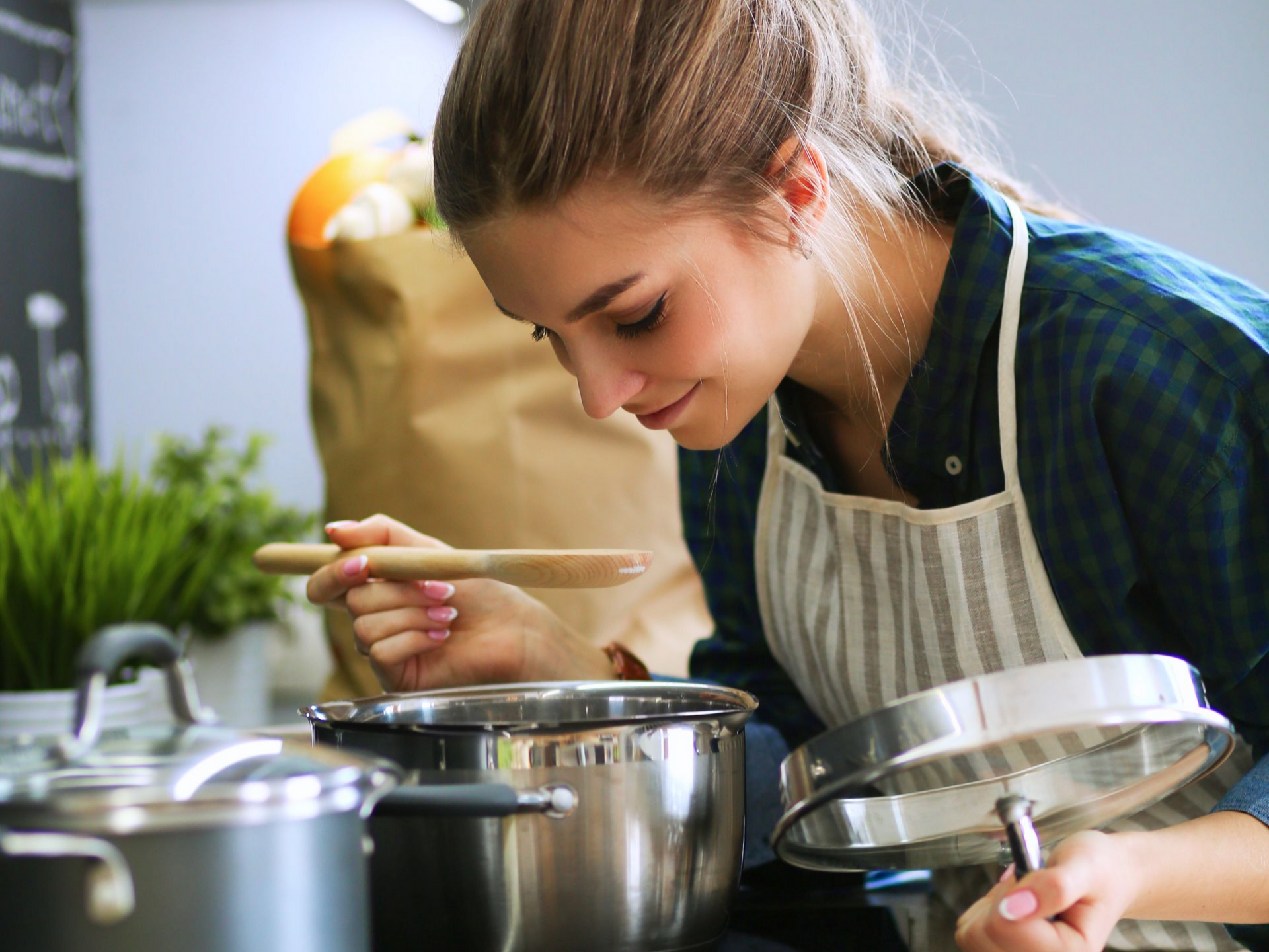 Personne en train de goûter le contenu d'une casserole avec une cuillère en bois