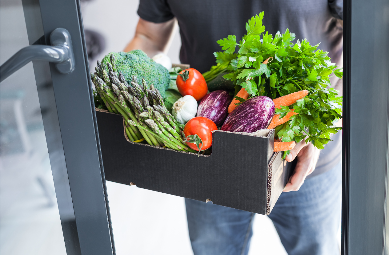 Personne livrant une caisse de légumes à la porte d'un client