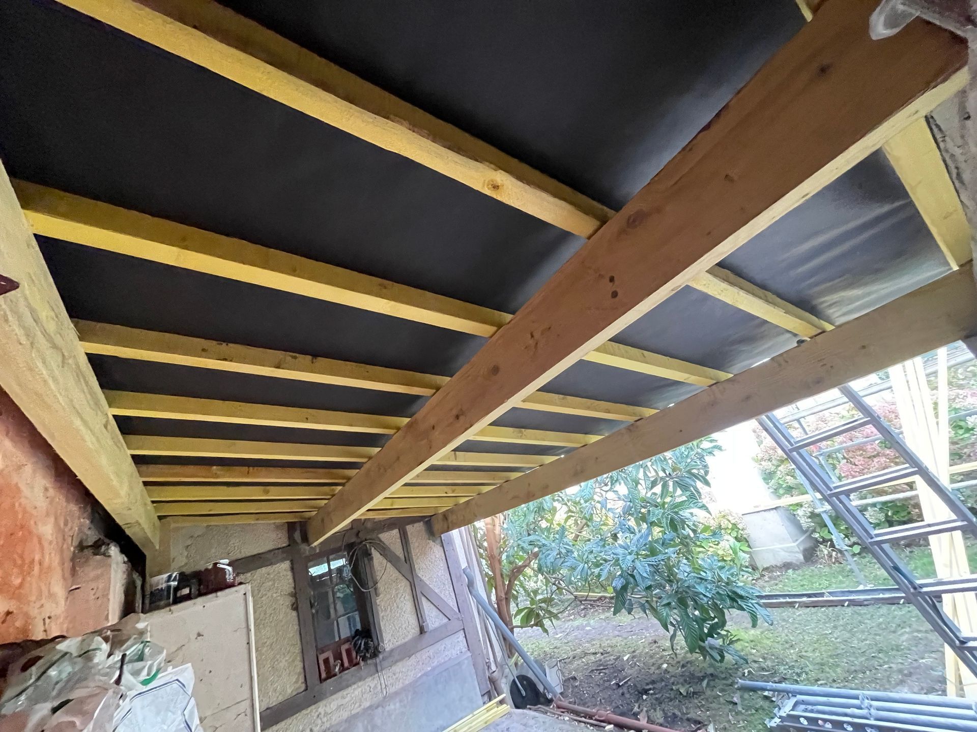 Des poutres en bois soutiennent le dessous d'une terrasse.