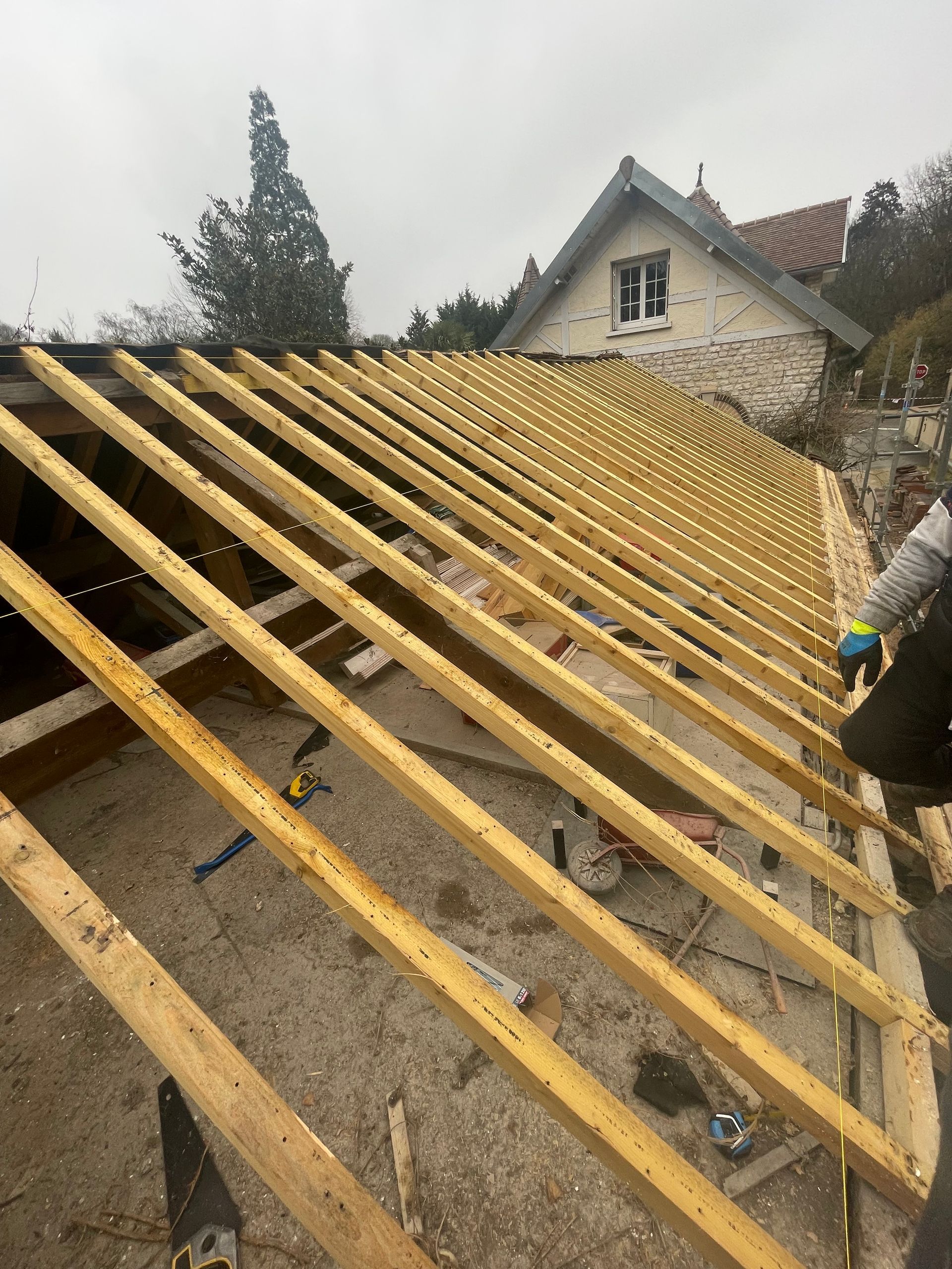 Charpente de toit en construction avec chevrons en bois apparents sur une maison