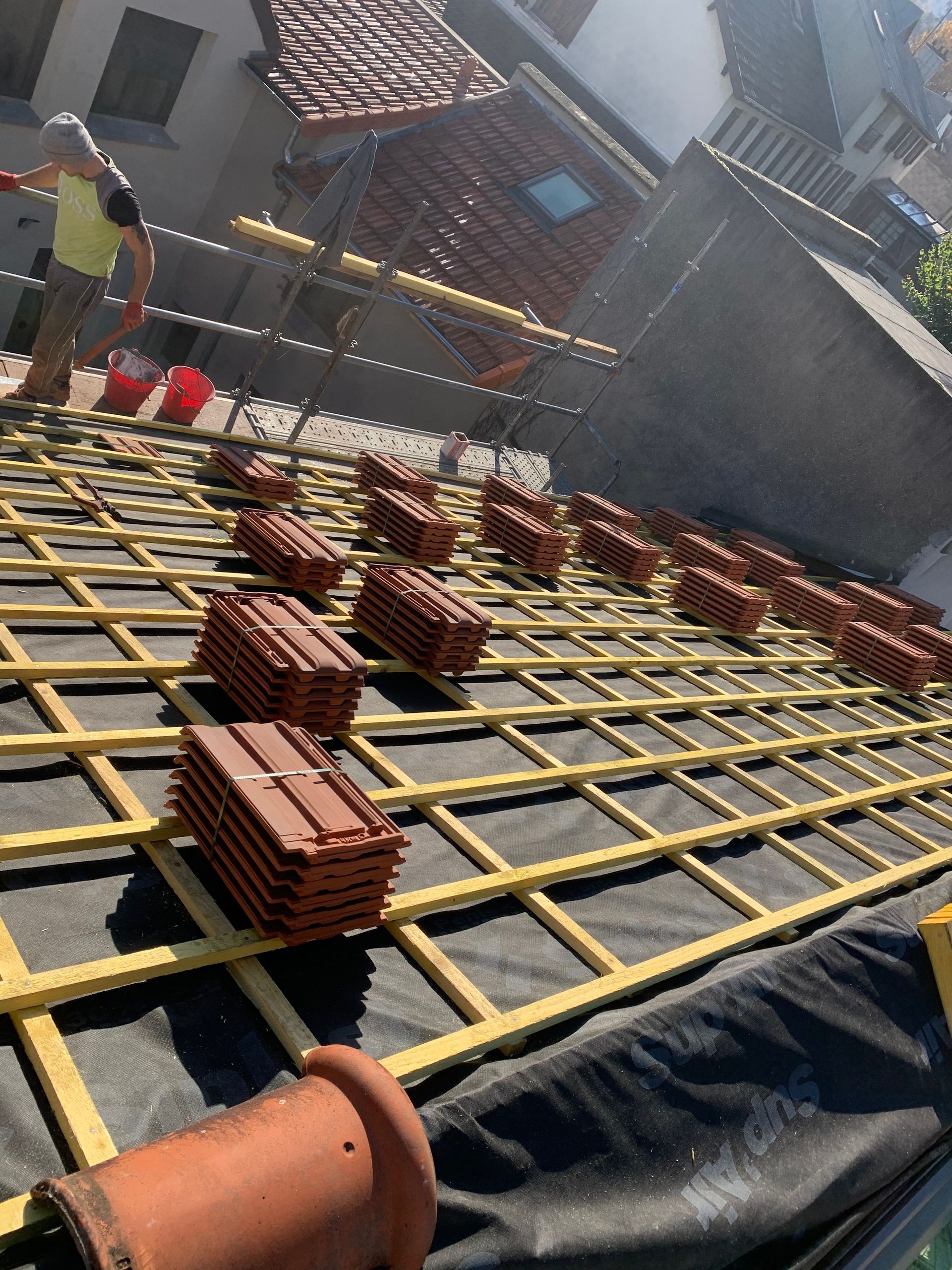 Chantier de construction avec treillis d'armature et piles de briques sur une terrasse de toit