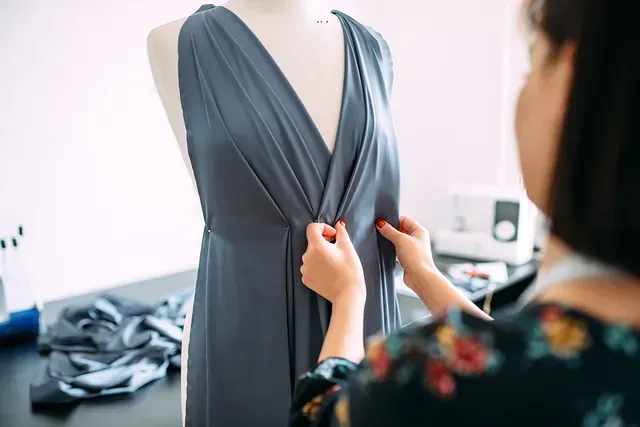 Una mujer está ajustando un vestido en un maniquí.