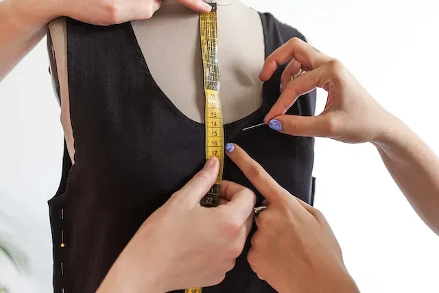 Una mujer está midiendo un vestido en un maniquí con una cinta métrica.