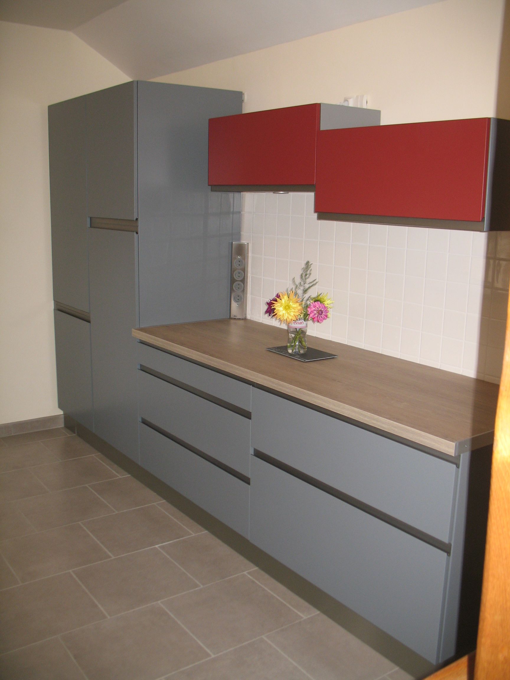 Cuisine moderne avec armoires grises, armoires suspendues rouges, comptoir clair et dosseret en carrelage.