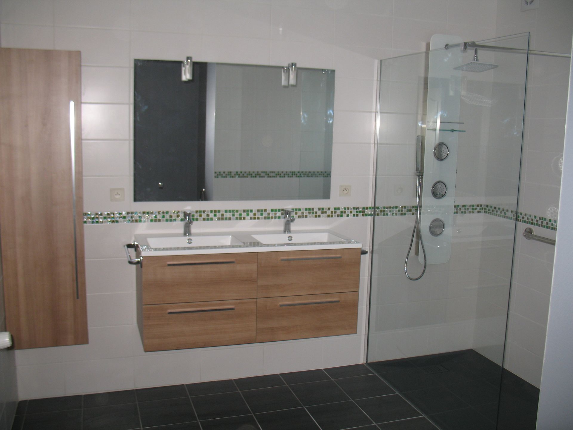 Salle de bain moderne avec meuble-lavabo double, douche en verre et armoire en bois.