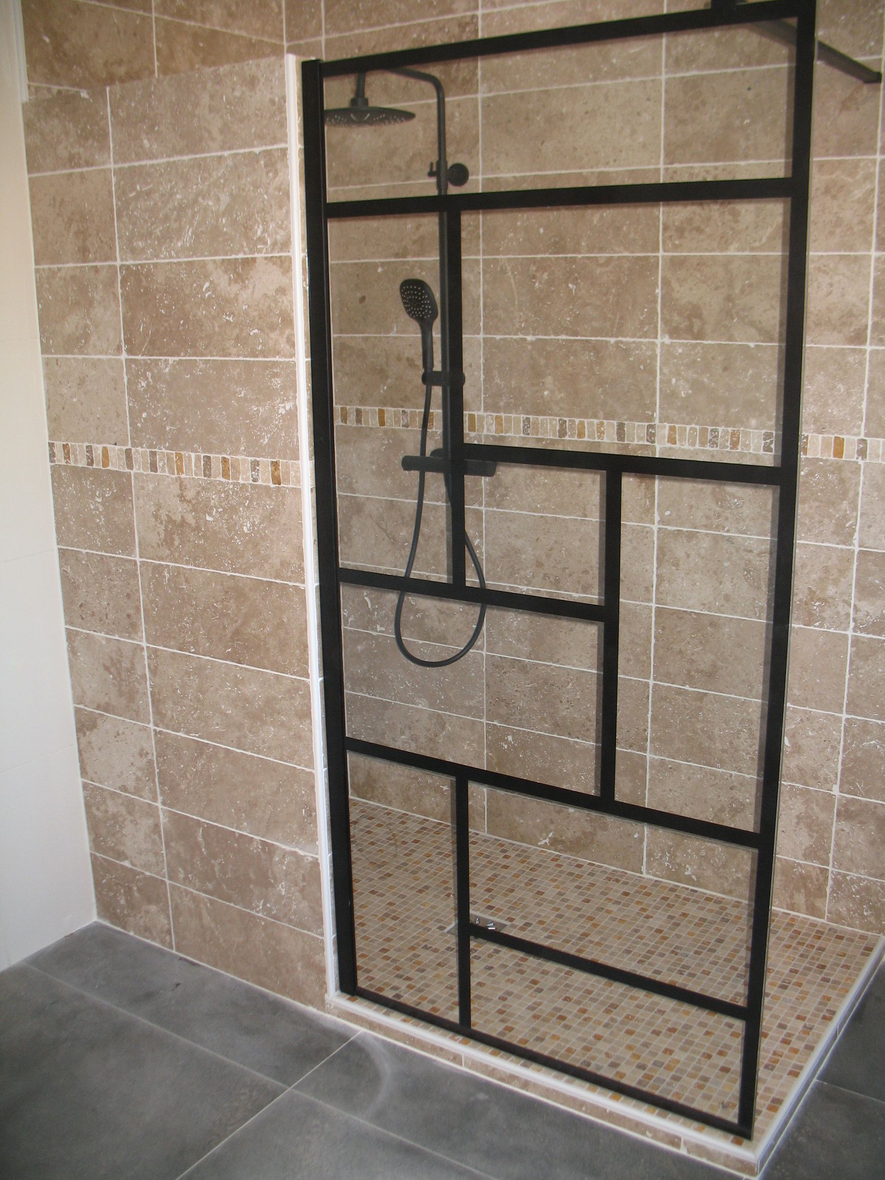 Cabine de douche avec cadre en métal noir et murs en carrelage beige.
