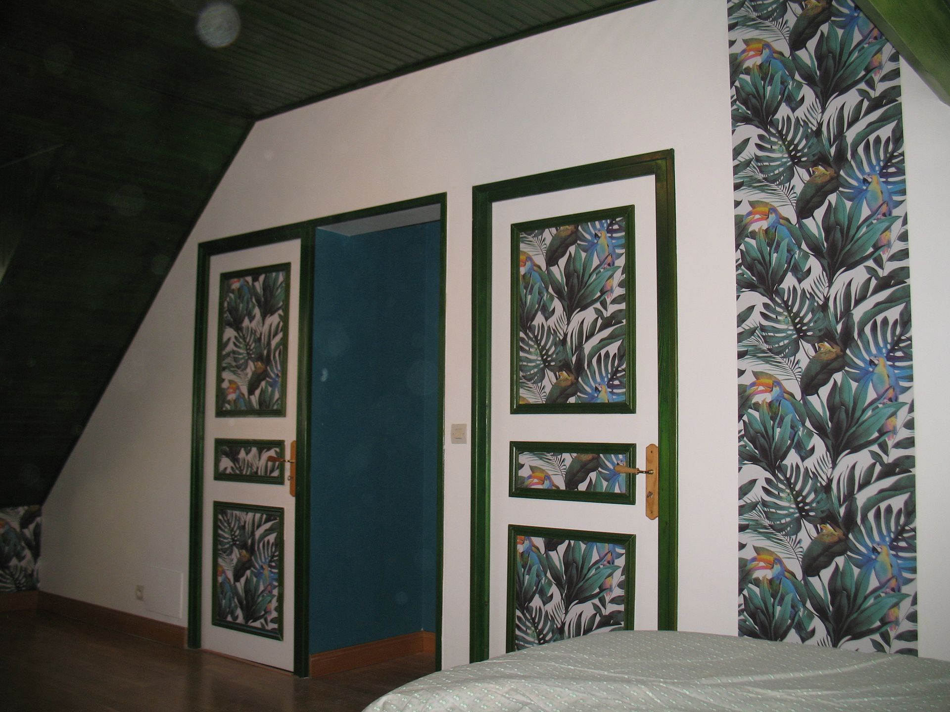Intérieur avec portes blanches ornées de feuilles tropicales, de garnitures vertes et d'un papier peint assorti.