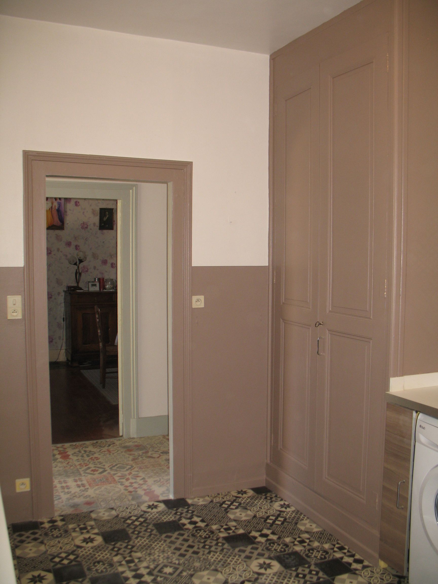 Vue intérieure d'une pièce avec des murs marron, une porte et un sol à motifs.