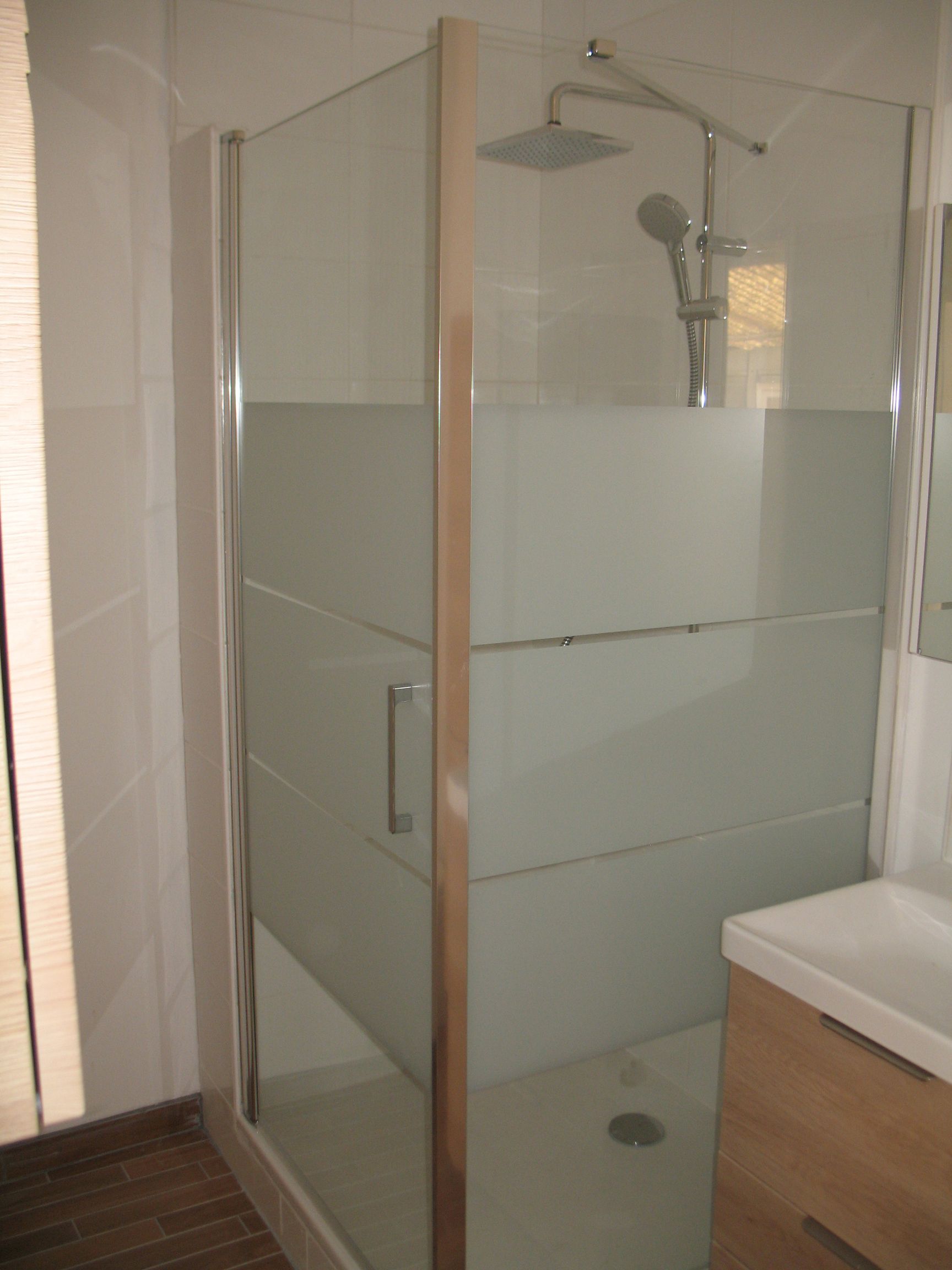 Cabine de douche avec verre dépoli et accessoires argentés.