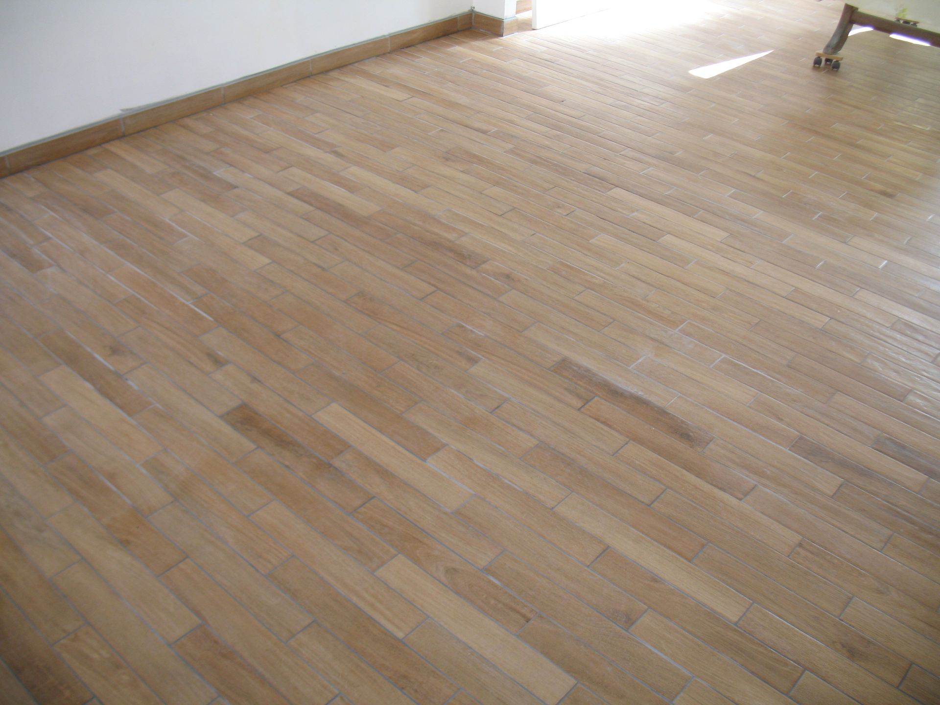 Plancher en bois dans une pièce, couleur marron clair, avec un mur en arrière-plan.