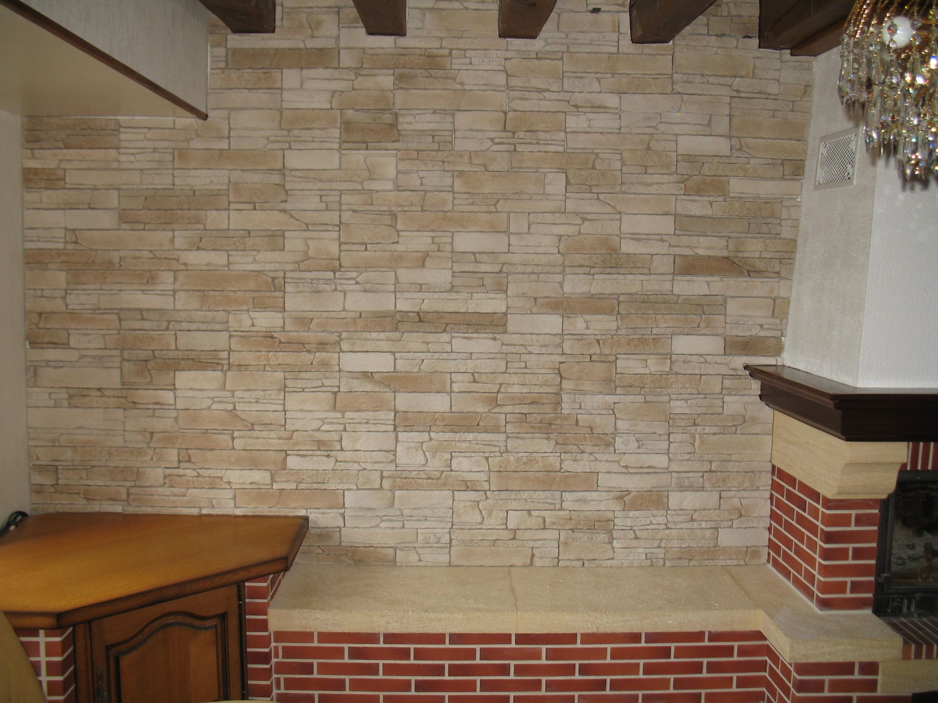 Mur revêtu de pierre avec une cheminée et des accents de poutres en bois, comprenant un foyer en brique et une armoire en bois.