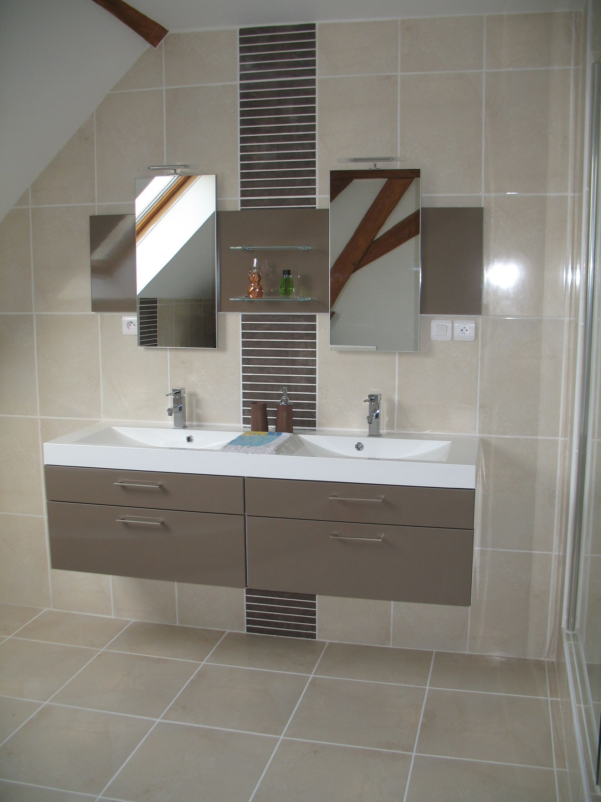 Salle de bain avec meuble-lavabo double, miroirs et touches de carrelage décoratif dans les tons beige et marron.