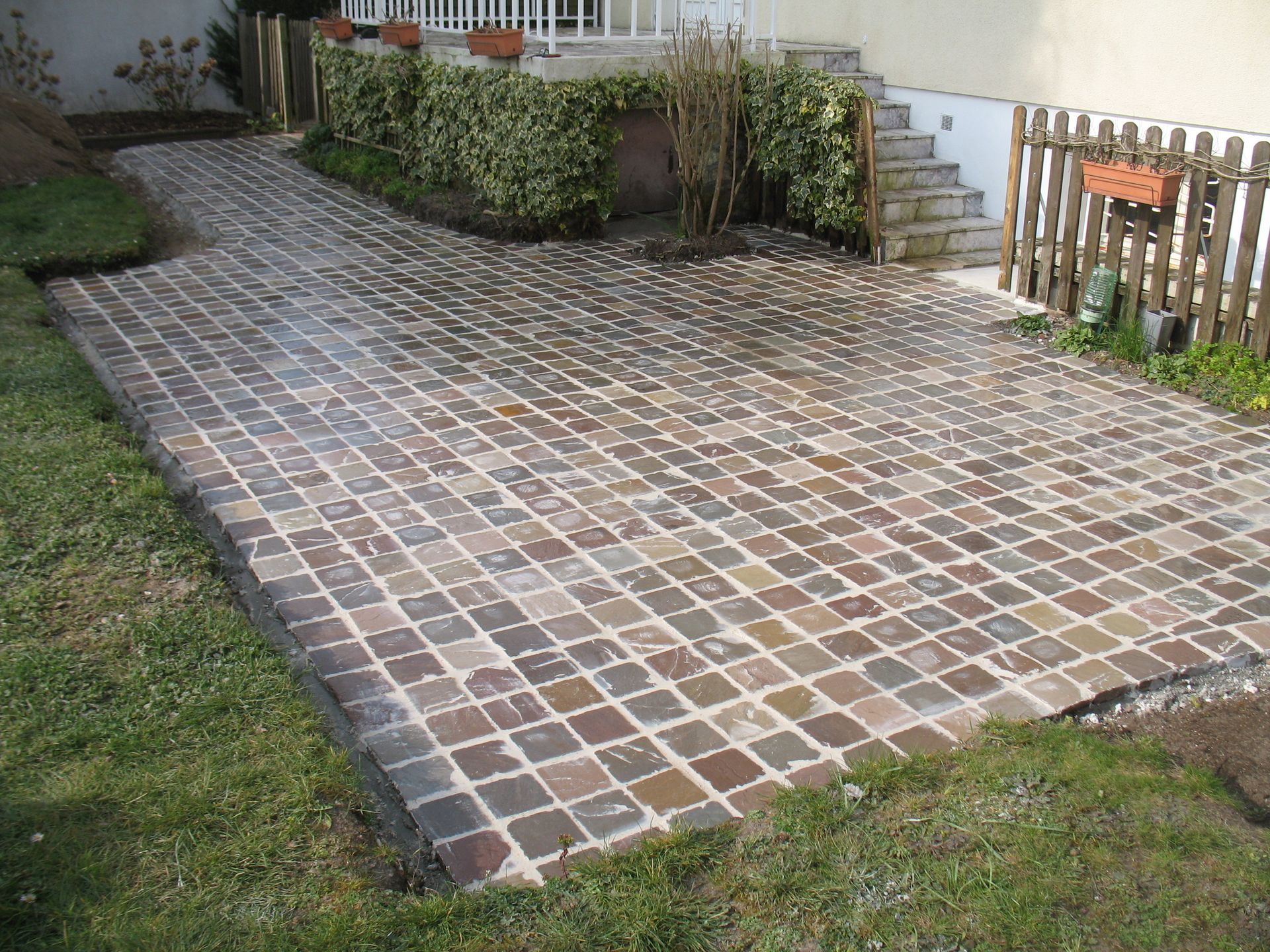 Patio en brique avec rampe, bordé de gazon et d'une maison.