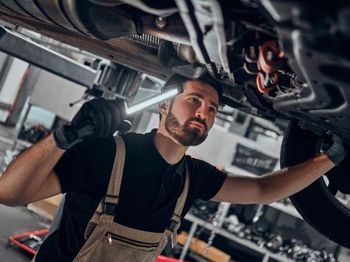 Un hombre está trabajando debajo de un coche en un garaje.