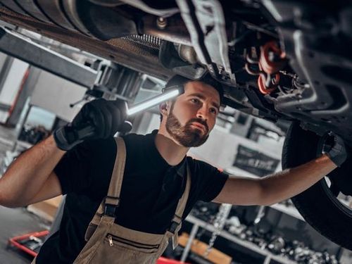 Un hombre está trabajando debajo de un coche en un garaje.