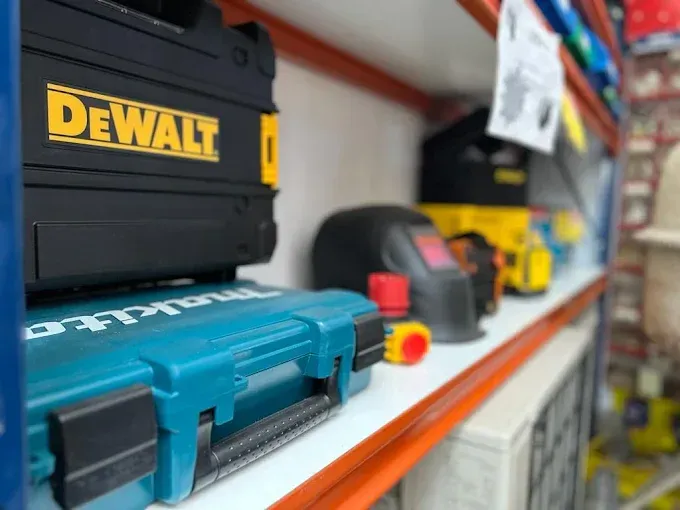 Una caja de herramientas Dewalt apilada sobre una caja Makita en el estante de una tienda