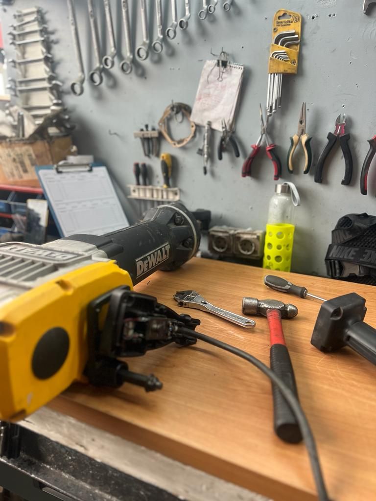 Una sierra de vaivén Dewalt, un martillo y herramientas pequeñas descansan sobre un banco de trabajo