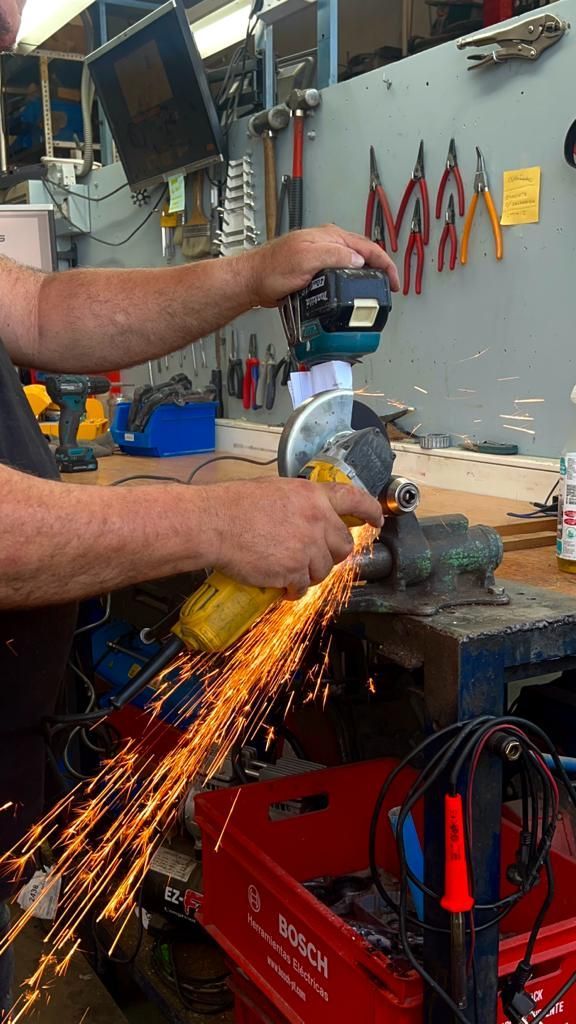 En un taller, persona utiliza  amoladora angular eléctrica amarilla para cortar metal, lo que produce una lluvia de chispas