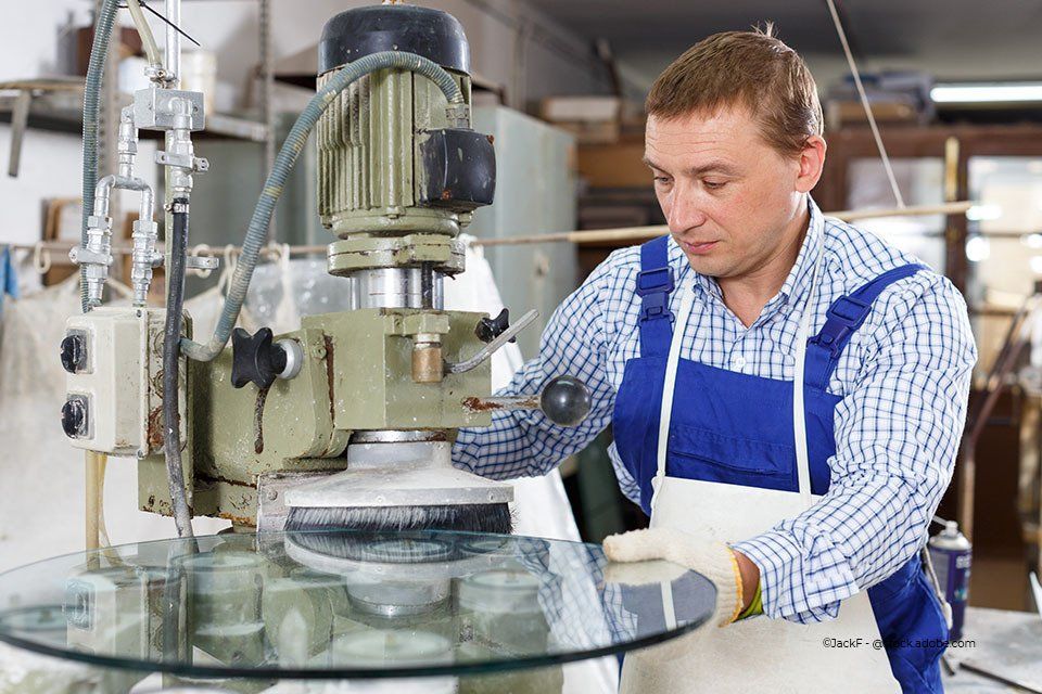 Mitarbeiter Aacotec Glasereigesellschaft mbH poliert Glas an einer Maschine