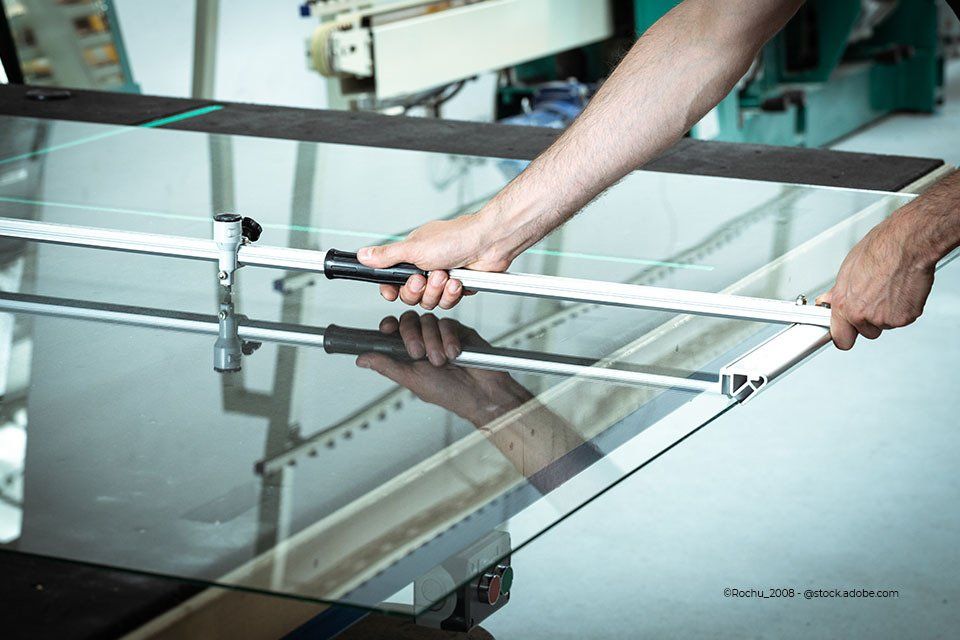 Mitarbeiter der Aacotec Glasereigesellschaft mbH befestigt Stützelement an einer Glasscheibe