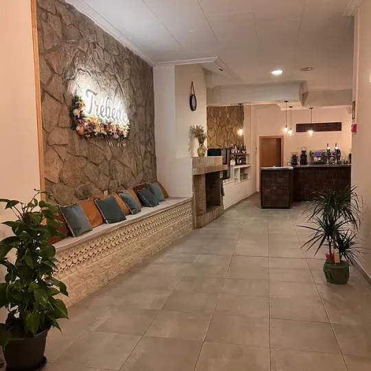 Un largo pasillo con una pared de piedra y un banco.