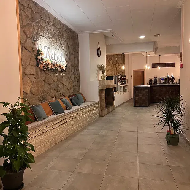 Un largo pasillo con una pared de piedra y un banco.