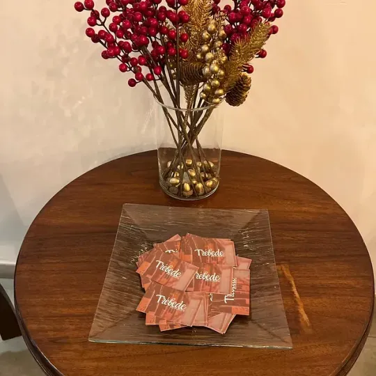 Una mesa de madera con un jarrón de bayas y un plato de Twizzlers.