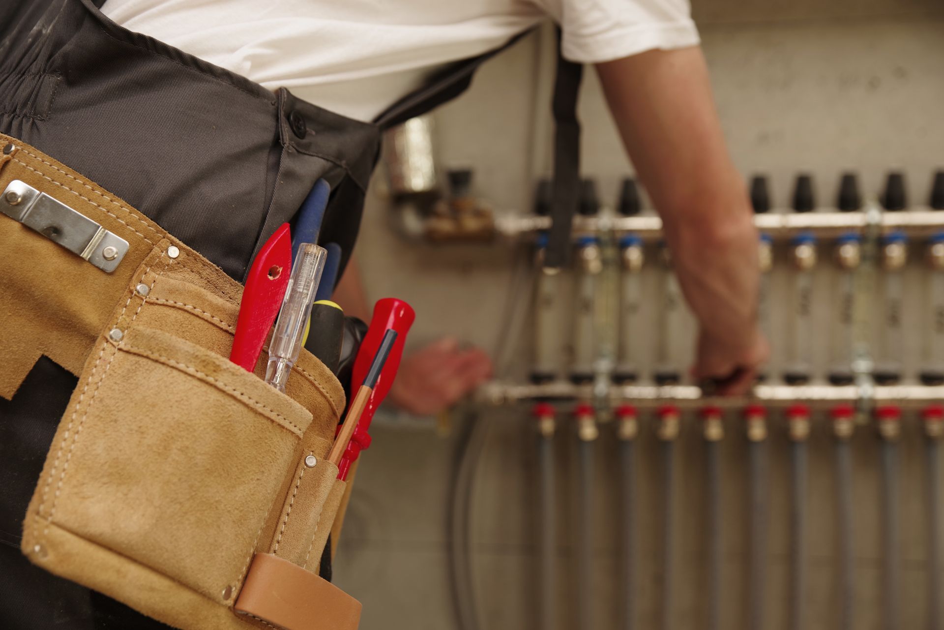 Un homme portant une ceinture à outils travaille sur un système de chauffage.
