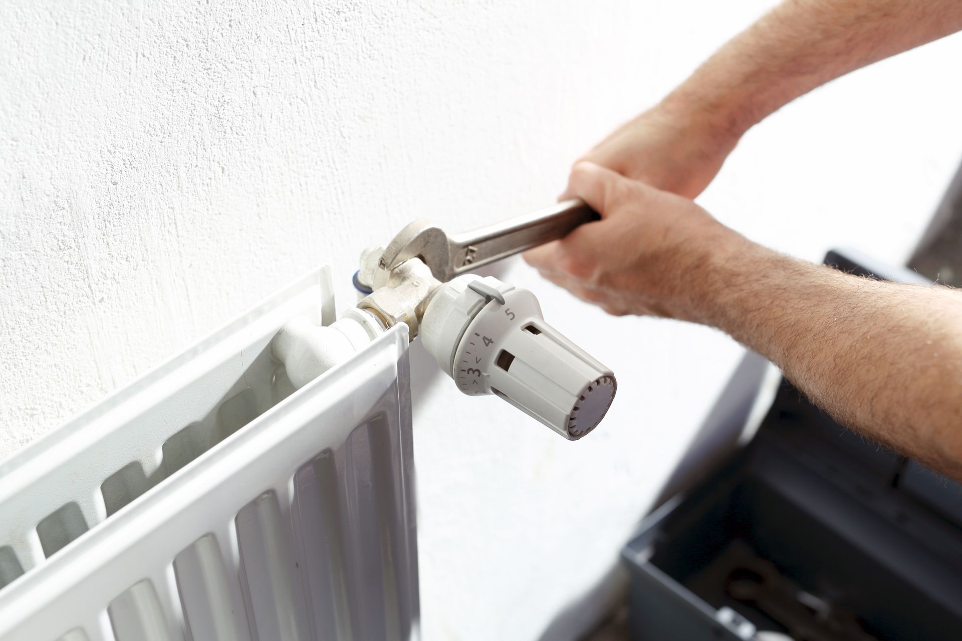 Un homme tient un thermomètre numérique devant un radiateur à gaz.