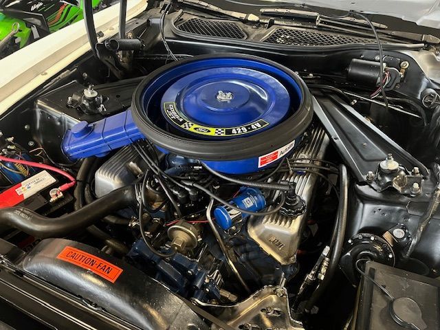 Moteur de voiture classique bleu et argent avec filtre à air bleu, dans le compartiment moteur d'une voiture.