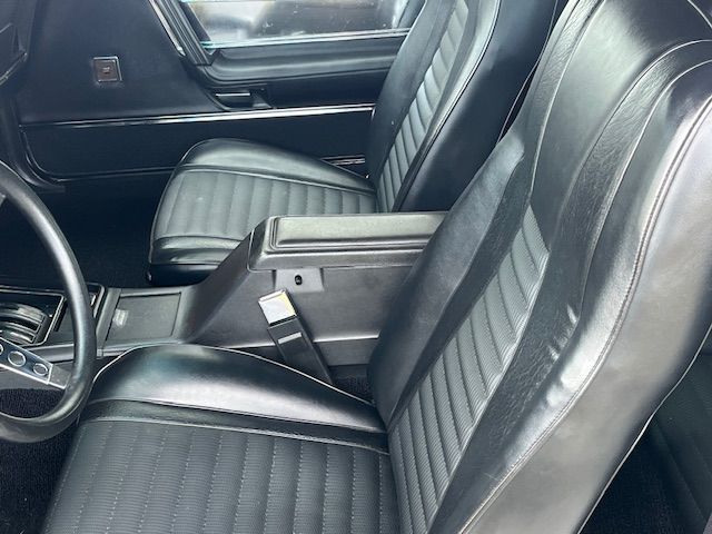 Intérieur noir de la voiture avec deux sièges baquets, une console centrale et un volant.