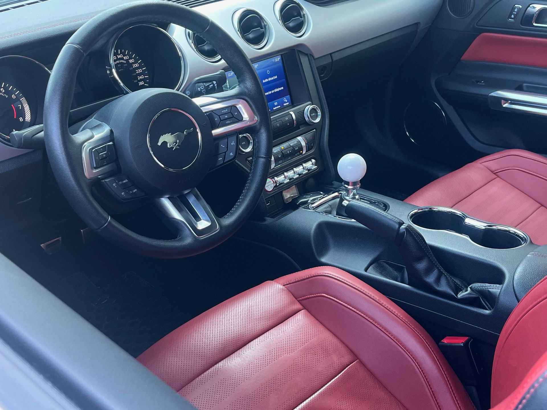 Intérieur en cuir rouge avec volant Mustang, console centrale et levier de vitesses manuel.