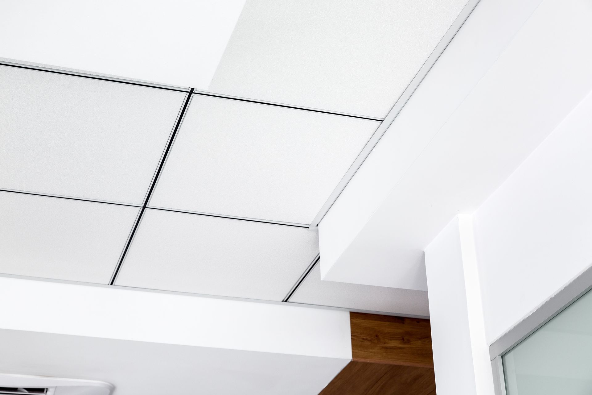 Plafond de bureau blanc avec une grille de panneaux carrés