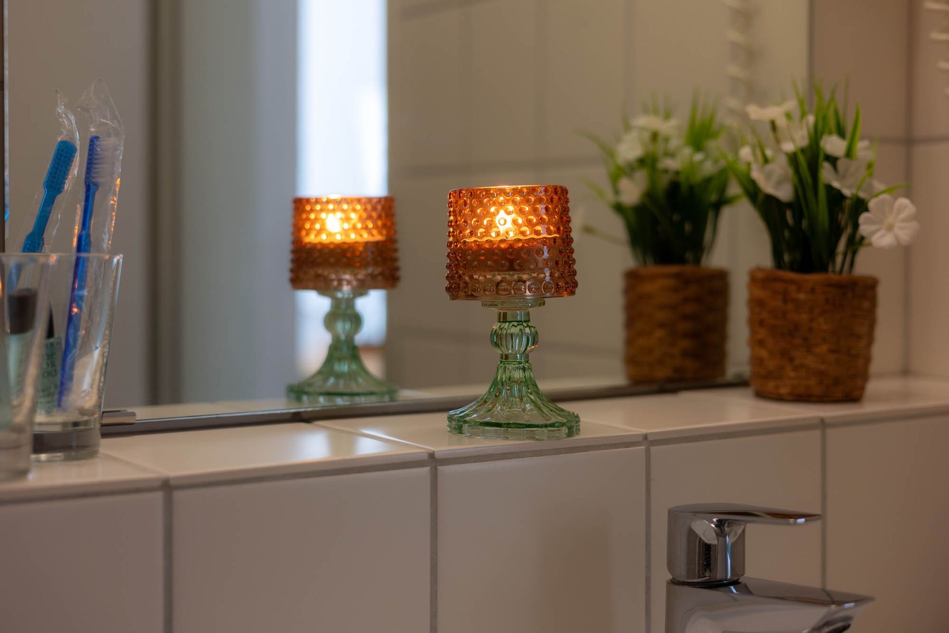 Auf der Ablage im Badezimmer stehen zwei Kerzen.