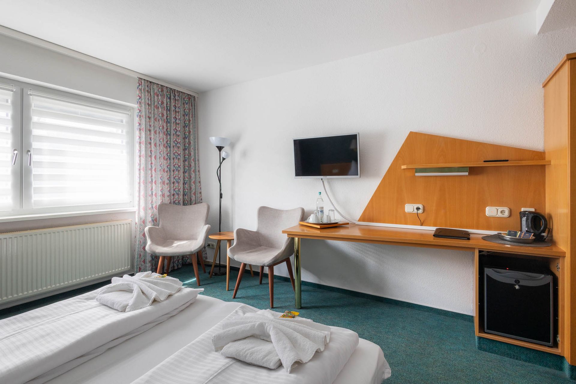 Ein Hotelzimmer mit Bett, Stühlen, Schreibtisch und Fernseher.