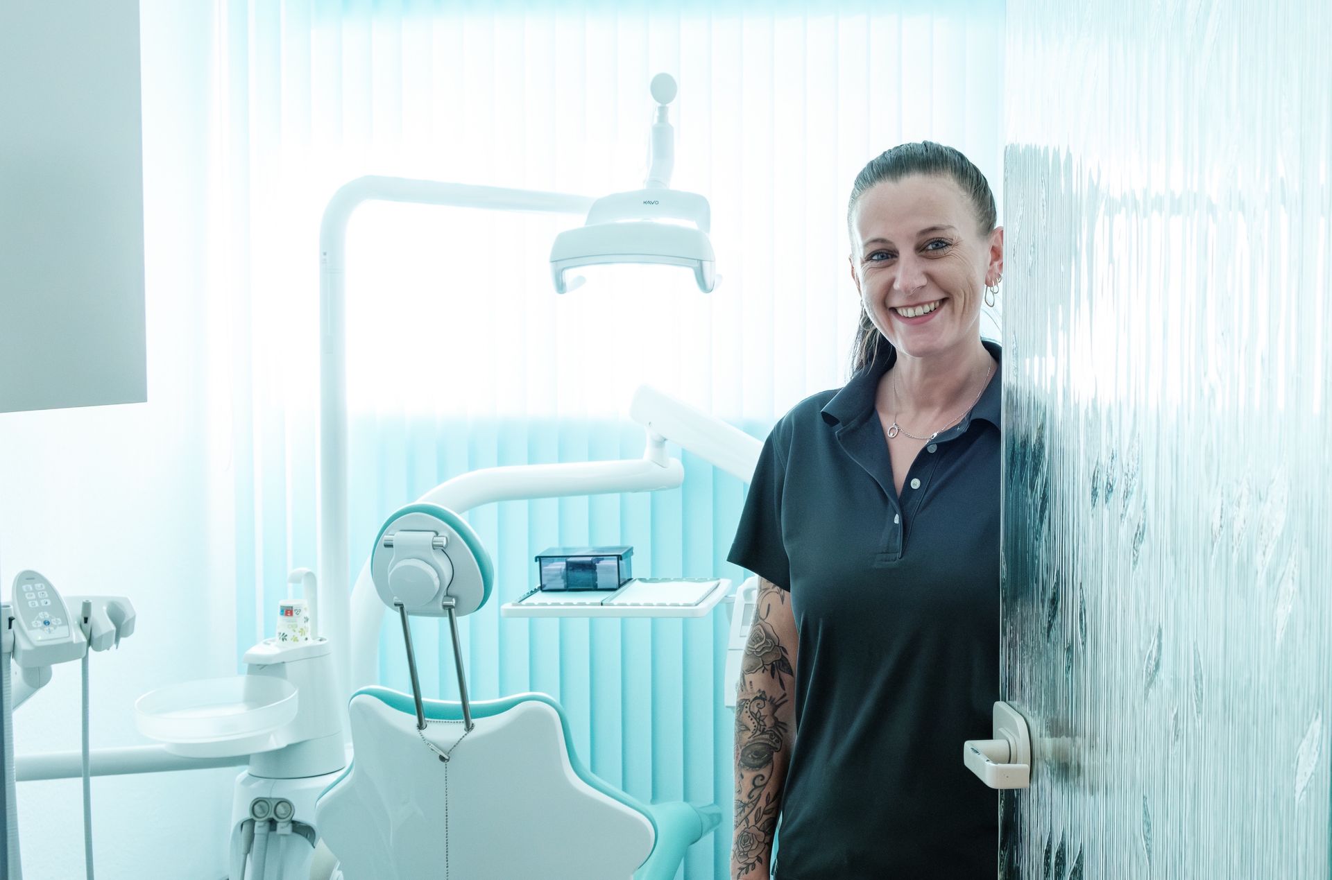 Eine Frau steht in einer Zahnarztpraxis hinter einer Glastür.