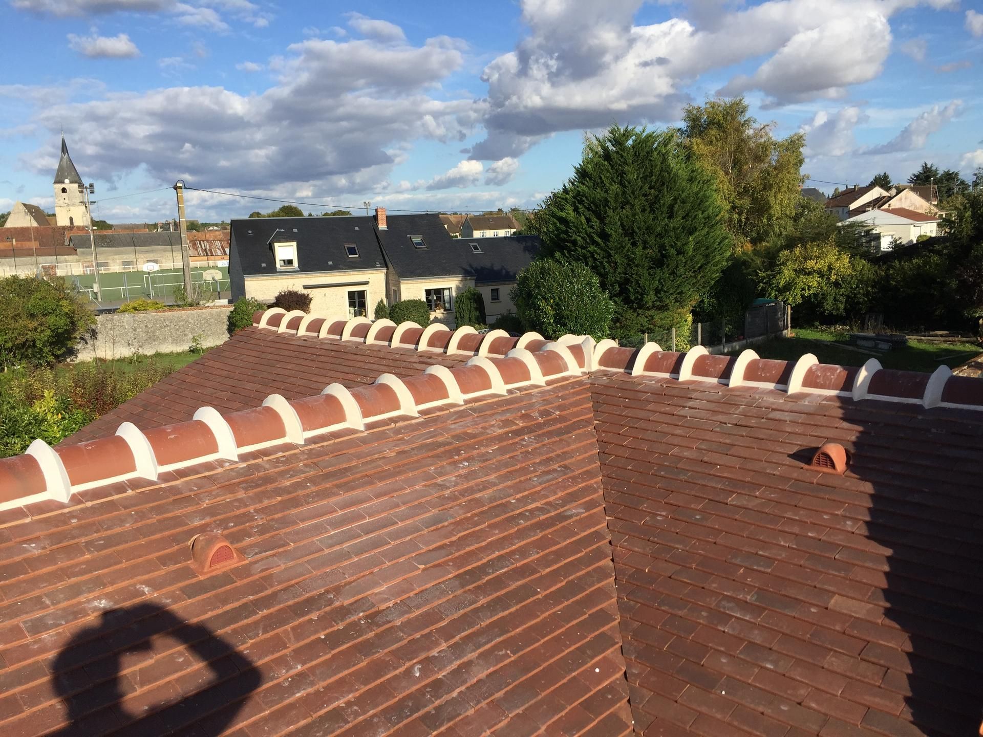 Vue depuis un toit en briques sur un quartier résidentiel sous un ciel partiellement nuageux