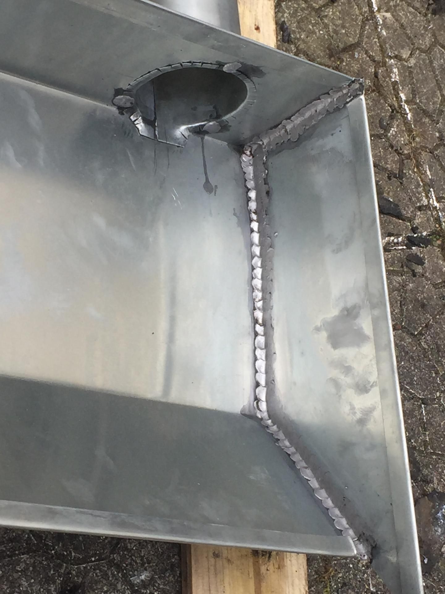 Coin de conduit métallique avec une soudure et une ouverture pour tuyau rond