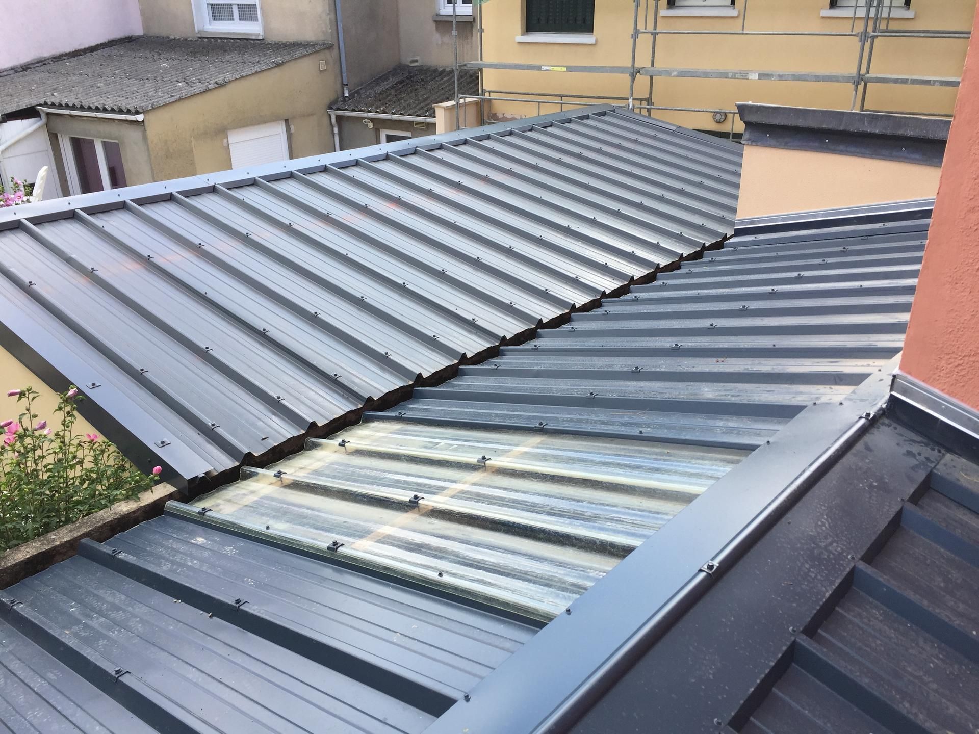 Toiture en métal gris inclinée avec panneaux superposés sur le toit d'un bâtiment