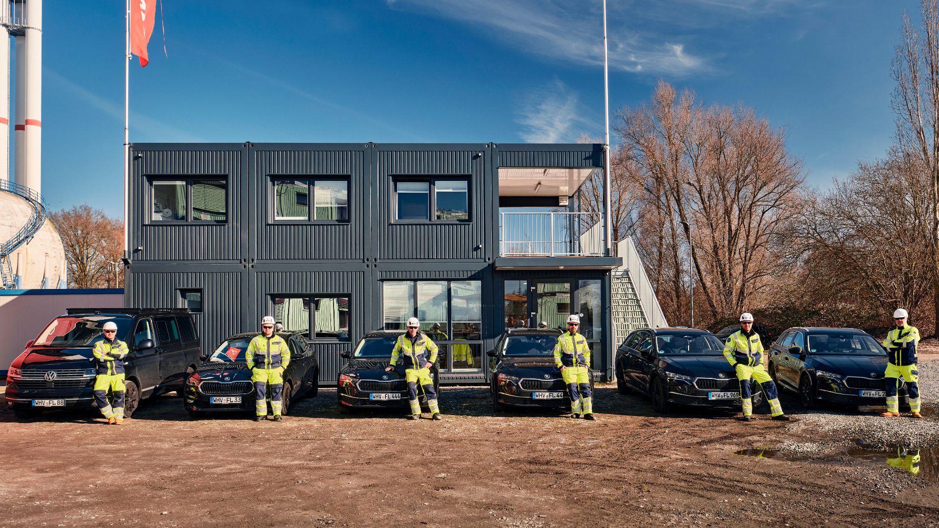 Group of people in blue shirts in front of a brick building; sign with blue logo.