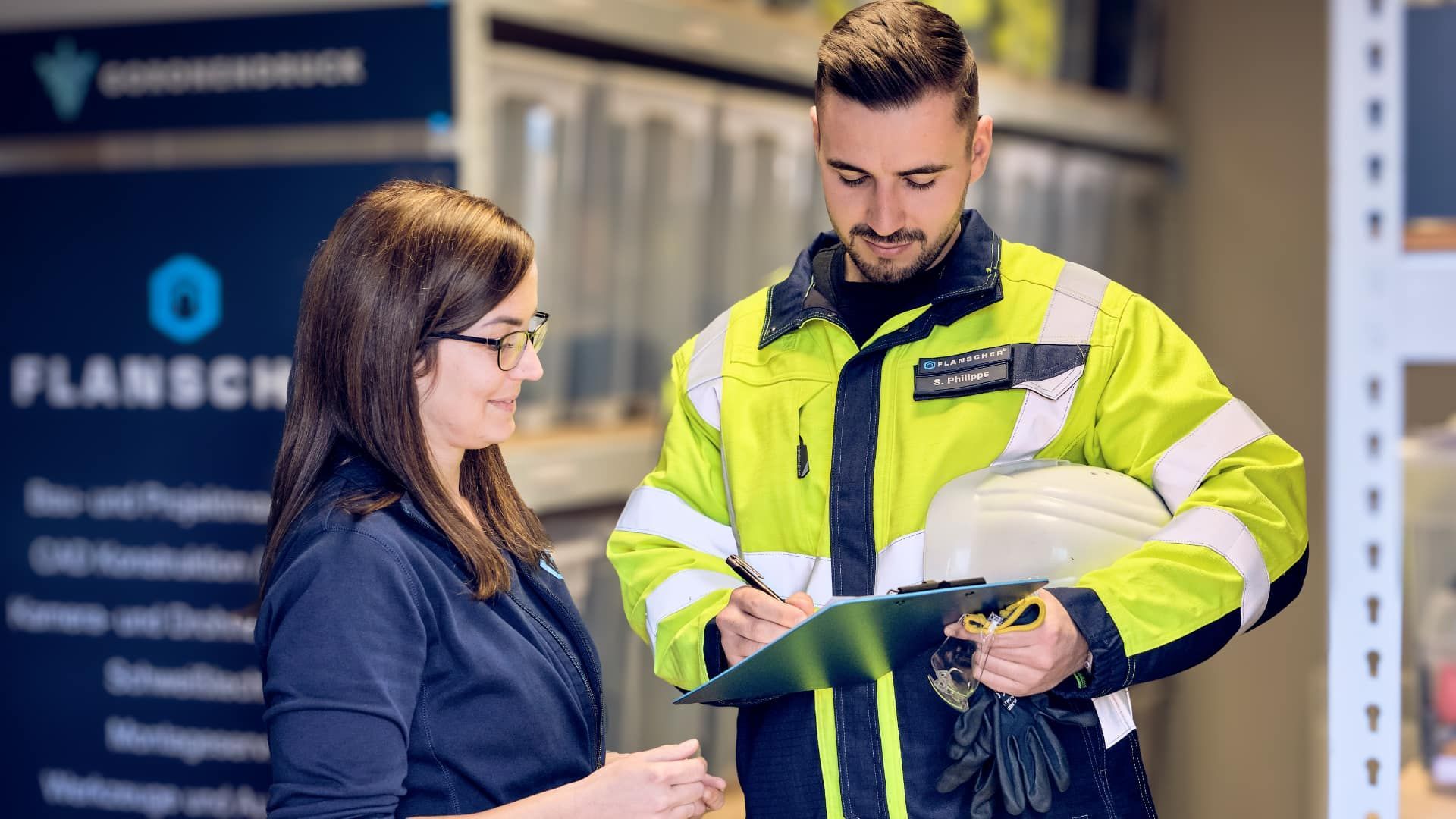 Man holding drone, looking at it, with monitors displaying aerial views, sitting at a desk.